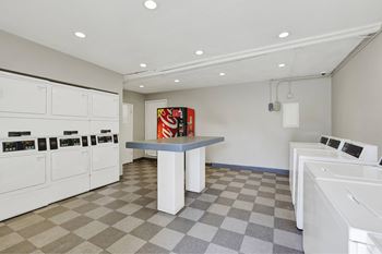 A laundromat with a checkered floor and washing machines on both sides.
