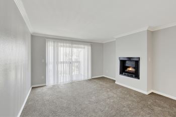 A living room with a fireplace and a window with blinds.