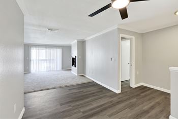 A room with a ceiling fan and light, a window with curtains, and a door.