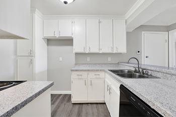 A kitchen with white cabinets and a granite countertop.