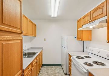 Gwynn Oak apartment for rent - A kitchen with white appliances and wooden cabinets.