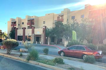 El Paso apartment for rent - A red car is parked on the side of the road in front of a building.