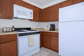 El Paso apartment for rent - A kitchen with a white refrigerator, a blue stove, and brown cabinets.