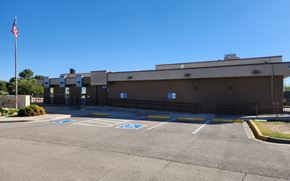 El Paso apartment for rent - A parking lot with a building and a flag in the background.