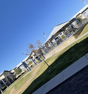 El Paso apartment for rent - A building with a blue roof and a white wall with a tree in front of it.