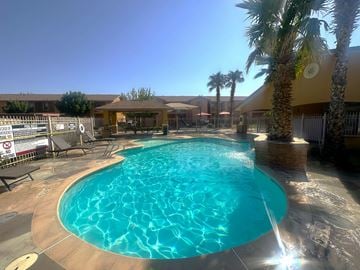 El Paso apartment for rent - A large outdoor swimming pool surrounded by palm trees and a sunny sky.