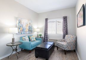 El Paso apartment for rent - A living room with a blue couch, a patterned chair, and a small table.
