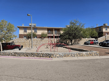 El Paso apartment for rent - A playground with a red swing set is in front of a building.