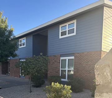 El Paso apartment for rent - A grey house with a brick wall and a large rock in front.