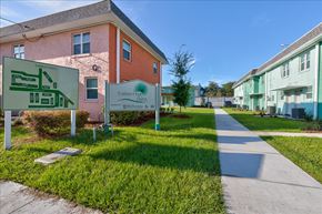 Jacksonville apartment for rent - A sign for Polkline Gardens is in front of a pink building.