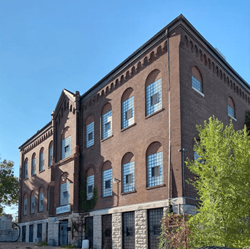 St. Louis apartment for rent - A large red brick building with many windows and a tree in front.