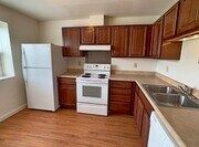 St. Louis apartment for rent - A kitchen with white appliances and wooden cabinets.