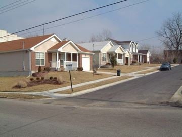 St. Louis apartment for rent - A street view of a residential area with houses and a car parked on the side.