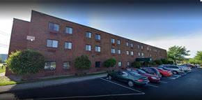 Louisville apartment for rent - Three-story brick apartment building with a front parking lot and green awning at the entrance