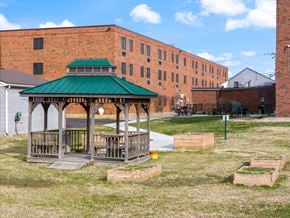 Louisville apartment for rent - Wooden gazebo and raised garden beds in courtyard near brick apartment buildings