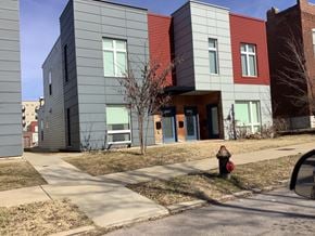 St. Louis apartment for rent - A fire hydrant is in front of a grey building with a red door.