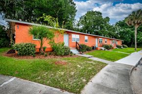 Jacksonville apartment for rent - A row of orange houses with green trees in the background.