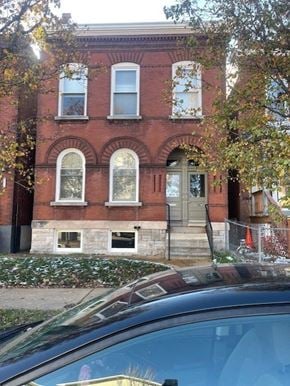 St. Louis apartment for rent - A red brick building with a black car in front.