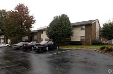 Hopkinsville apartment for rent - Two cars parked in a parking lot in front of a building.