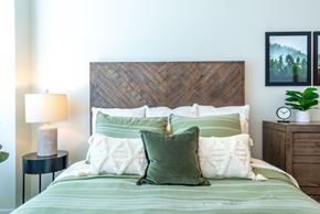 Lakeville apartment for rent - a bedroom with a bed with green pillows and a wooden headboard