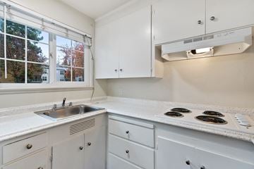 Fremont apartment for rent - A kitchen with white cabinets and a stove top oven.