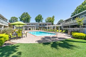 Fremont apartment for rent - A swimming pool surrounded by a grassy area and a yellow umbrella.