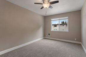 Castro Valley apartment for rent - A room with a ceiling fan and a window showing a view of houses and trees outside.