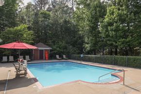 Richmond apartment for rent - a swimming pool with a red umbrella and chairs around it