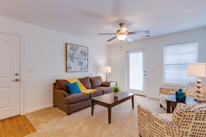Richmond apartment for rent - A living room with a brown couch, a coffee table, and a ceiling fan.