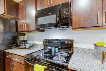 Richmond apartment for rent - A black microwave is mounted above a stove in a kitchen.