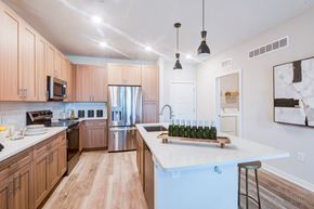 Orlando apartment for rent - A kitchen with wooden cabinets and a white quartz island at Tapestry Nona in Orlando, FL