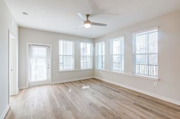 Oversized living room with natural light, ceiling fan, and balcony access.