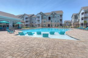 Burleson apartment for rent - a resort style swimming pool with chaise lounge chairs and umbrellas