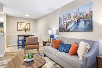 Greenville apartment for rent - A living room with a grey couch, a coffee table, and a painting of a cityscape on the wall.