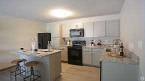 Vestavia Hills apartment for rent - Kitchen with black appliances, wood-designed flooring, and granite countertops at Avia Apartments in Vestavia Hills, AL