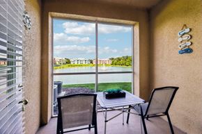 Ormond Beach apartment for rent - A patio with a table and chairs overlooking a pool and buildings.