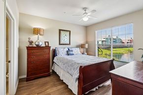 Ormond Beach apartment for rent - A bedroom with a bed, dresser, and window overlooking a lawn.