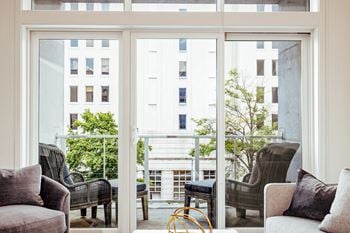 A living room with a couch and chairs and a balcony