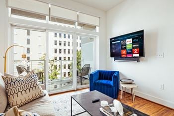 A living room with a couch and a chair and a tv on the wall