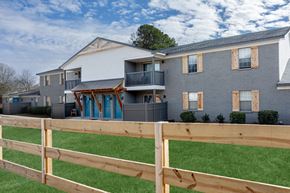 Athens townhouse for rent - A wooden fence in front of a grey building at Magnolia Apartments in Athens, Alabama