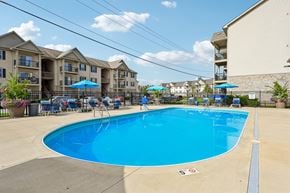 Columbus apartment for rent - A swimming pool surrounded by chairs and umbrellas in front of apartment buildings.