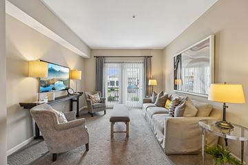 Columbus apartment for rent - A well-lit, spacious living room with a grey sofa, a grey armchair, a grey coffee table, and a painting on the wall.