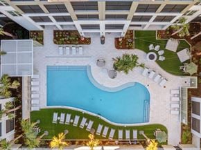 Orange Beach apartment for rent - A large outdoor swimming pool surrounded by a white tile patio and lounge chairs.