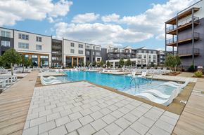 Birmingham apartment for rent - A large outdoor swimming pool with a wooden deck in front of apartment buildings.