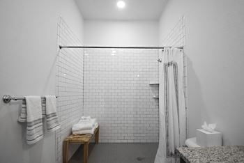 A white bathroom with a shower and a table with towels