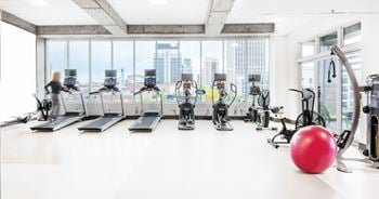 A gym with cardio machines and a red ball on the floor