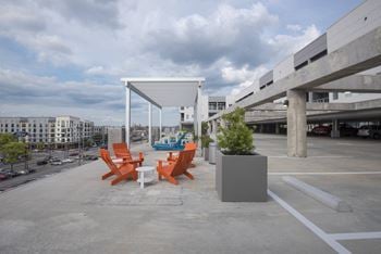 The terrace of a parking garage with orange chairs and a table