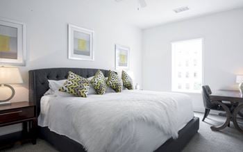 A bedroom with a large bed and a desk with a chair