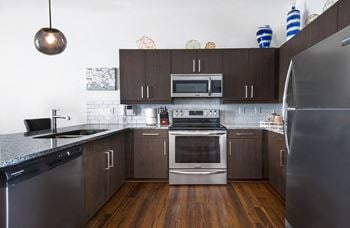 A kitchen with stainless steel appliances and dark wood cabinets