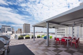 A rooftop patio with tables and chairs and a city in the background
